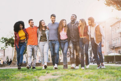 Mixed race group of friends having fun walking outdoors hand on shoulders